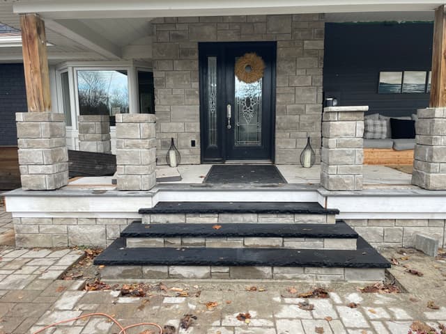 Rock-faced stone veneer wrapping the porch piers and skirt, with dark stone treads set on the three entry steps. — Georgian Bay, Ontario