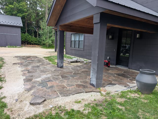 Granite flagstone walkway finished from under the porch out to the drive, joints swept tight and the outside edge bedded into gravel. — Collingwood, Ontario