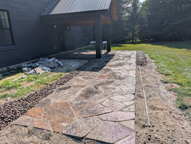 Finished granite flagstone walkway with a river rock border down one side. — Collingwood, Ontario