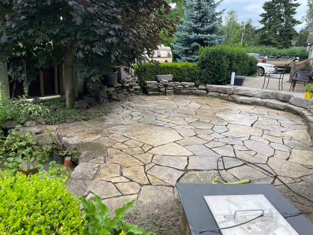 Flagstone patio washed clean, its irregular stones tight jointed and edged by a stacked stone wall. — Georgian Bay, Ontario