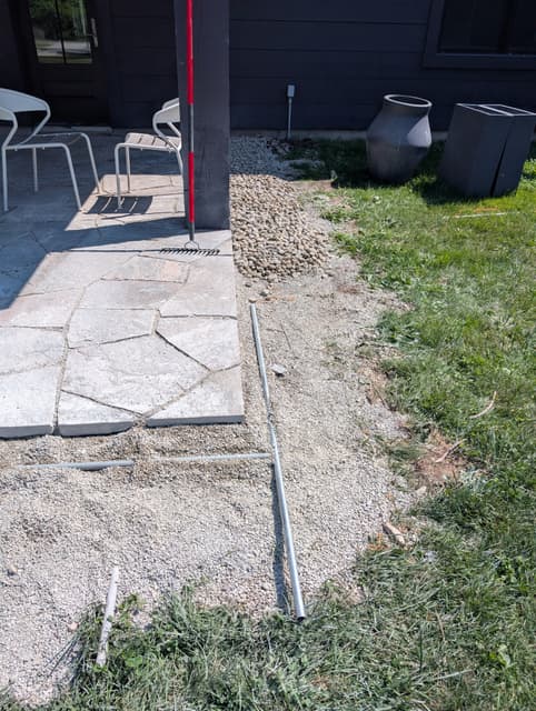 Screed rails laid across the compacted base alongside the finished flagstone edge. — Collingwood, Ontario