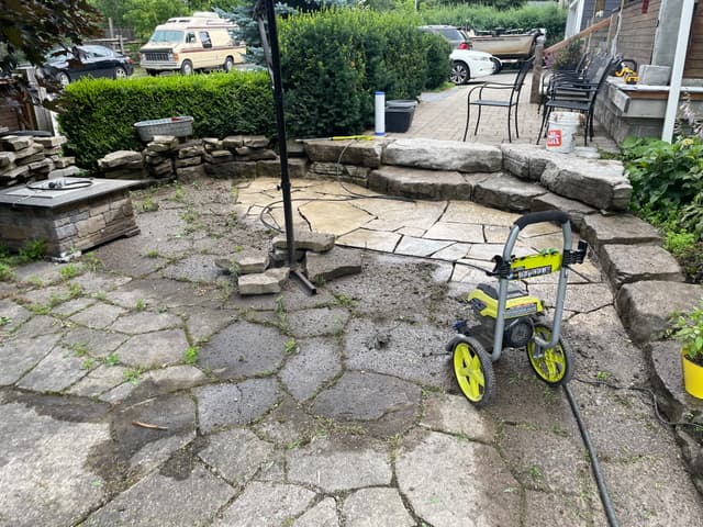 Flagstone patio part way through pressure washing, with the cleaned stone showing against the untouched section. — Georgian Bay, Ontario