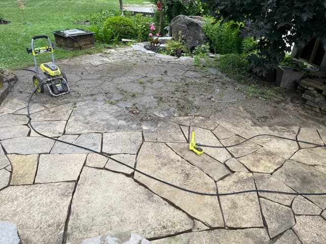 Existing flagstone patio under pressure washing, weeds and debris pulled out of the joints. — Georgian Bay, Ontario