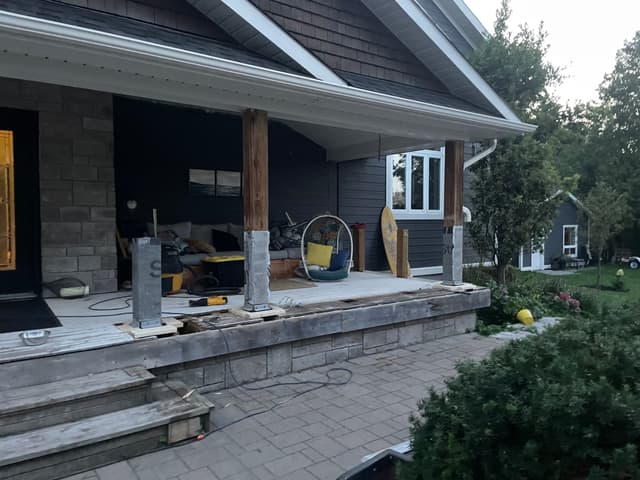 Covered porch stripped back to its framing, the timber posts left standing while the column bases are built up. — Georgian Bay, Ontario