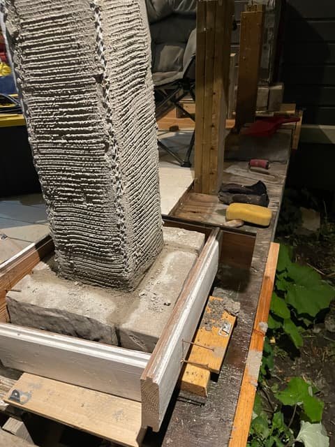Combed mortar scratch coat over lath on a porch column, sitting on its stone base. — Georgian Bay, Ontario