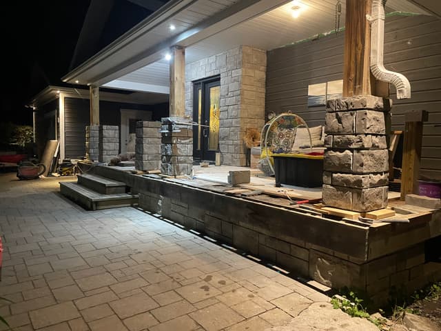 Column blocks stacked along the porch edge, paver walkway already laid in front. — Georgian Bay, Ontario