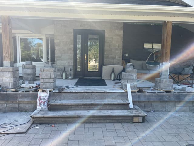 Stone column bases built up across the front of the covered porch, picking up the grey stone on the house wall. — Georgian Bay, Ontario