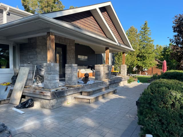 Stone-clad columns and the low porch wall taking shape, paver patio laid up to the steps. — Georgian Bay, Ontario