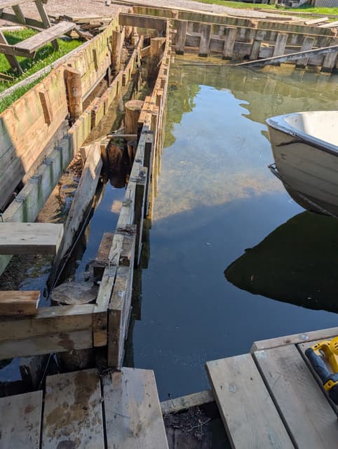 Dock stripped back to its timber cribbing, framing beams laid across the cut-off piles. — Georgian Bay, Ontario