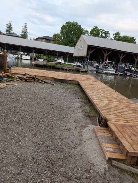 The rebuilt dock follows the shoreline, with timber steps down to the gravel. — Georgian Bay, Ontario